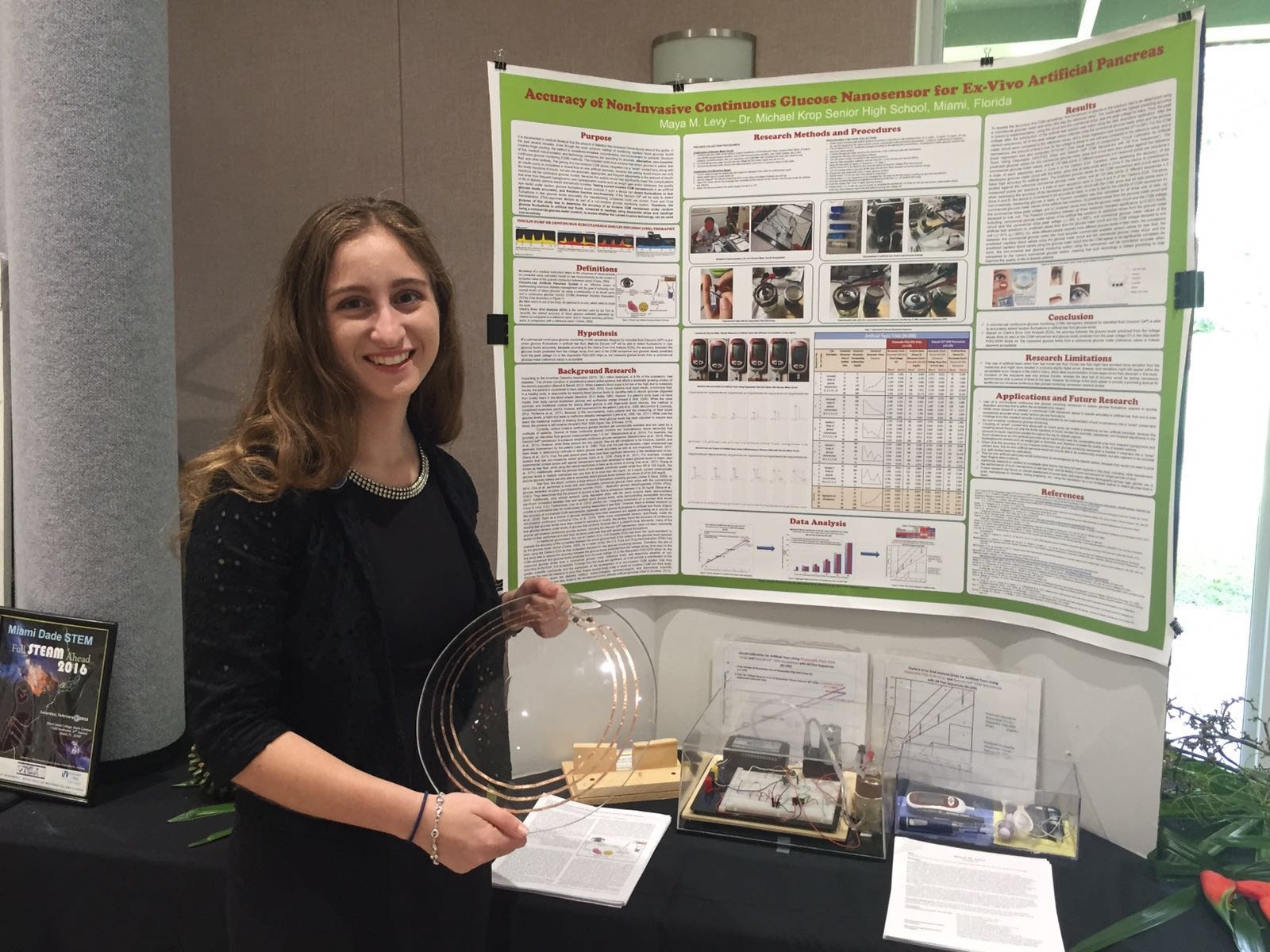 Maya with research poster and device at ISEF